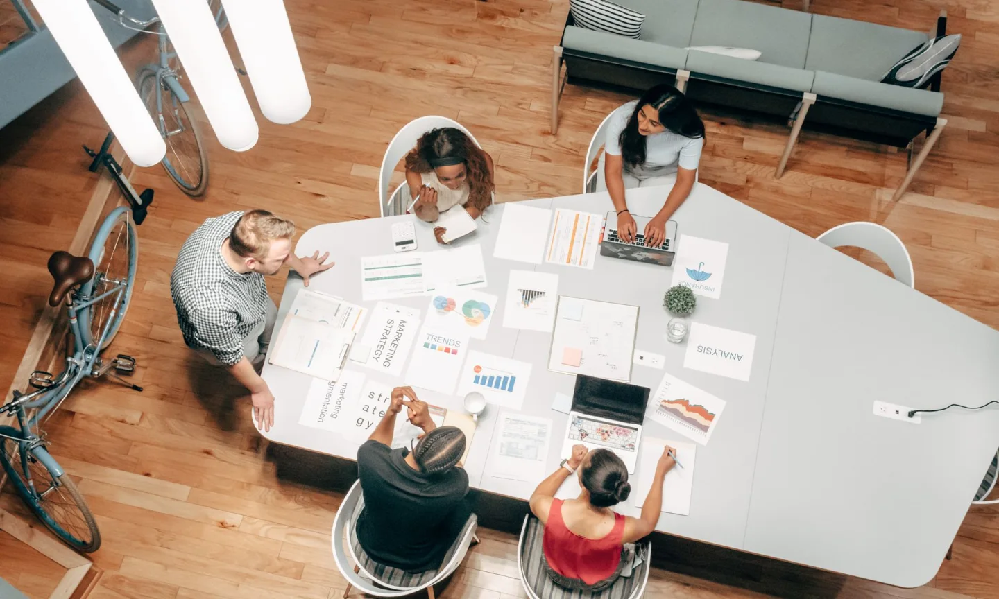 Overhead view of a team meeting with documents and laptops