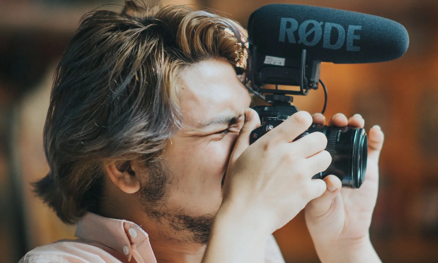 A camera operator filming with a microphone mounted above the camera