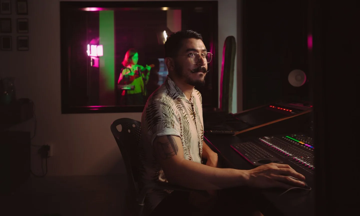 An audio producer working at a console in a colored-light studio