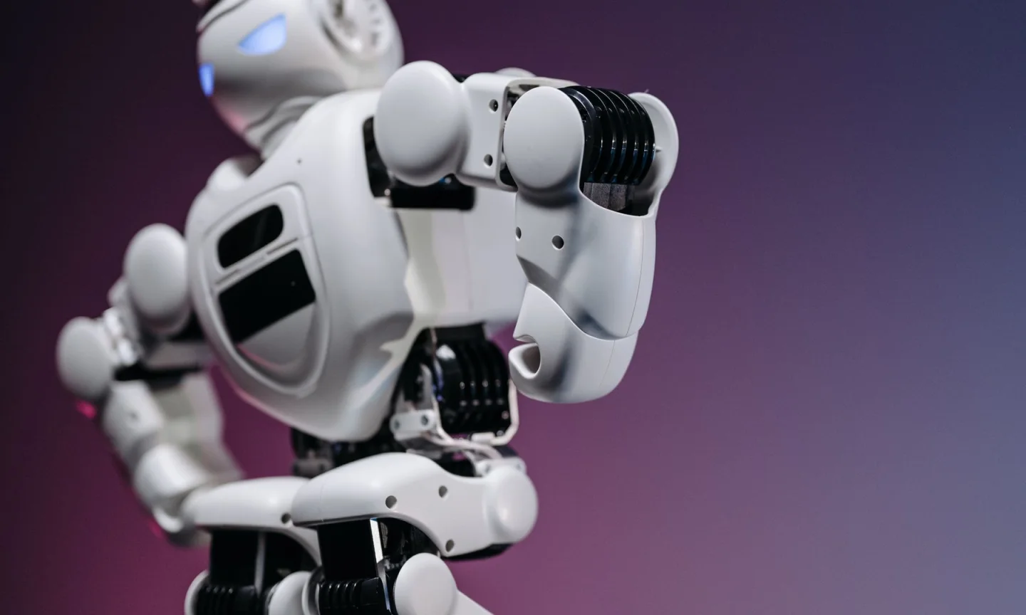 A small robot against a pink and purple background