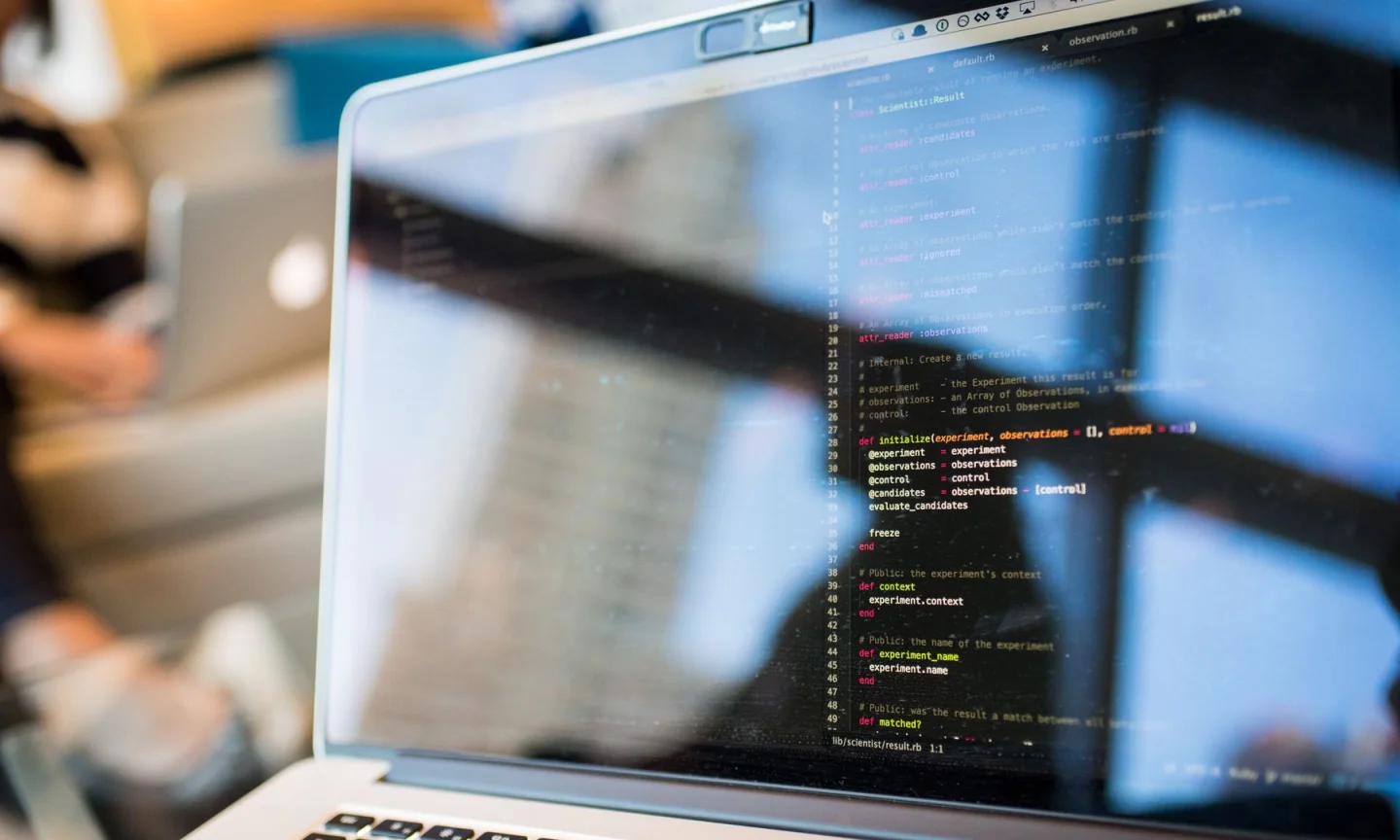 Code and room reflections on a laptop display