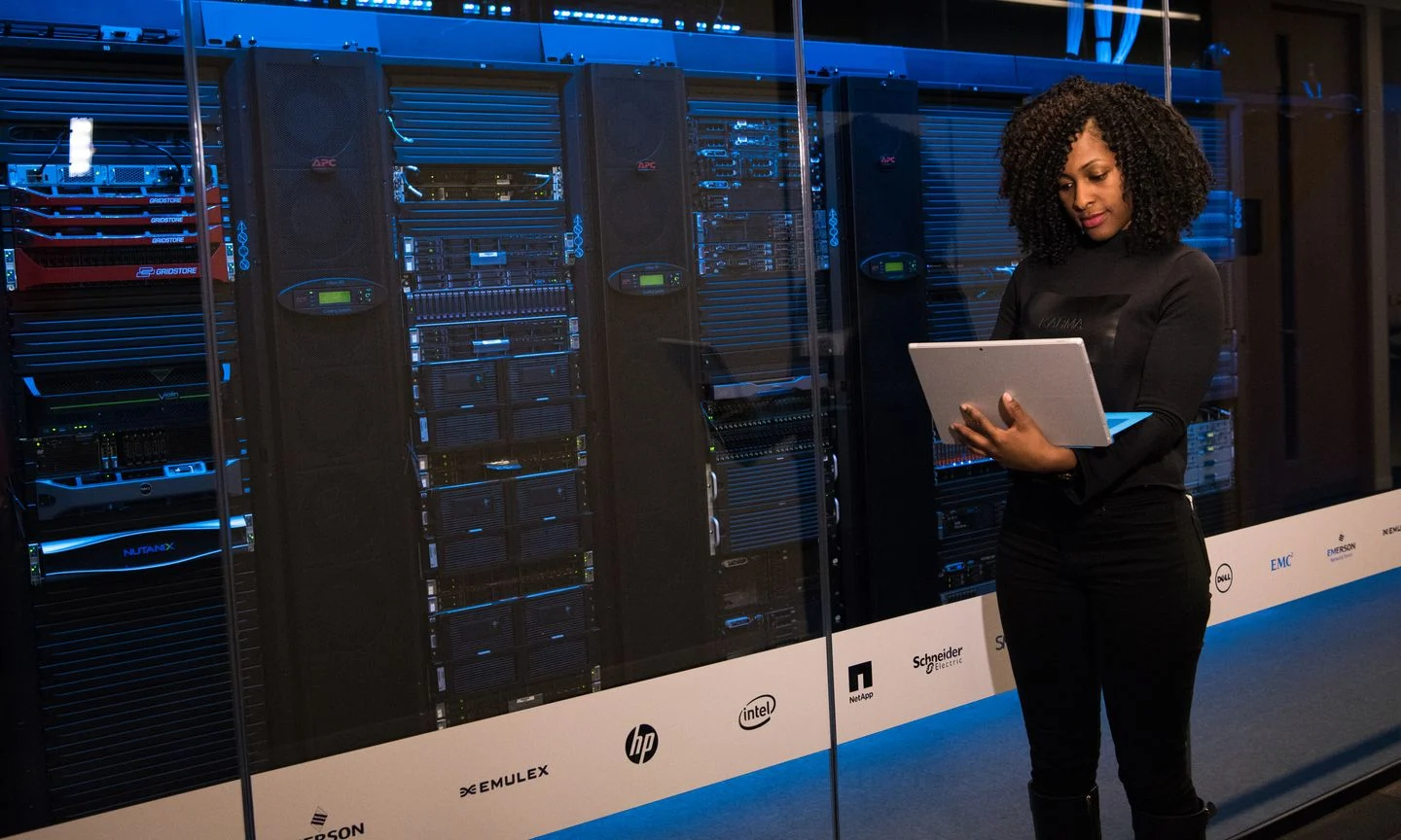 A technician with a laptop beside server racks