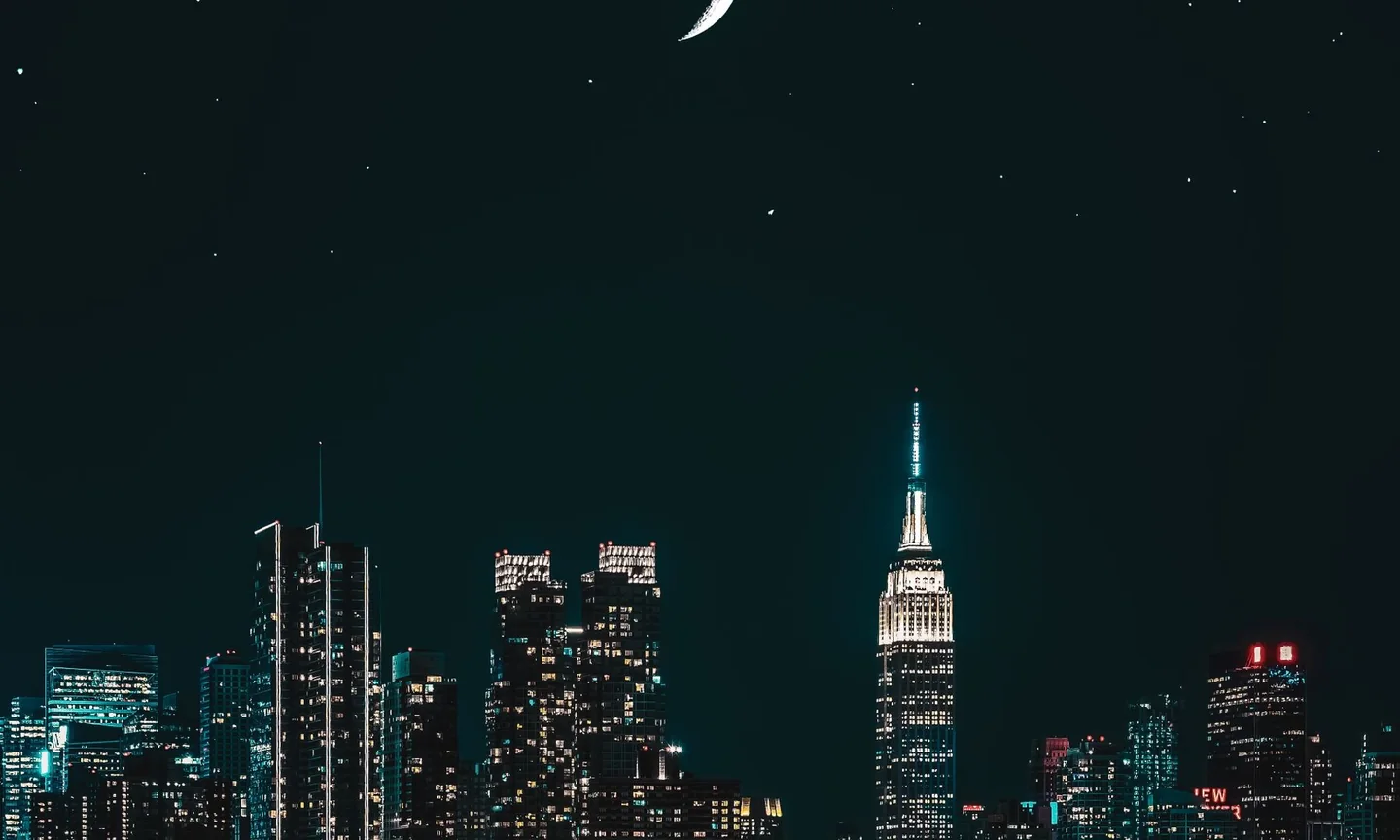 New York skyline illuminated at night under a crescent moon