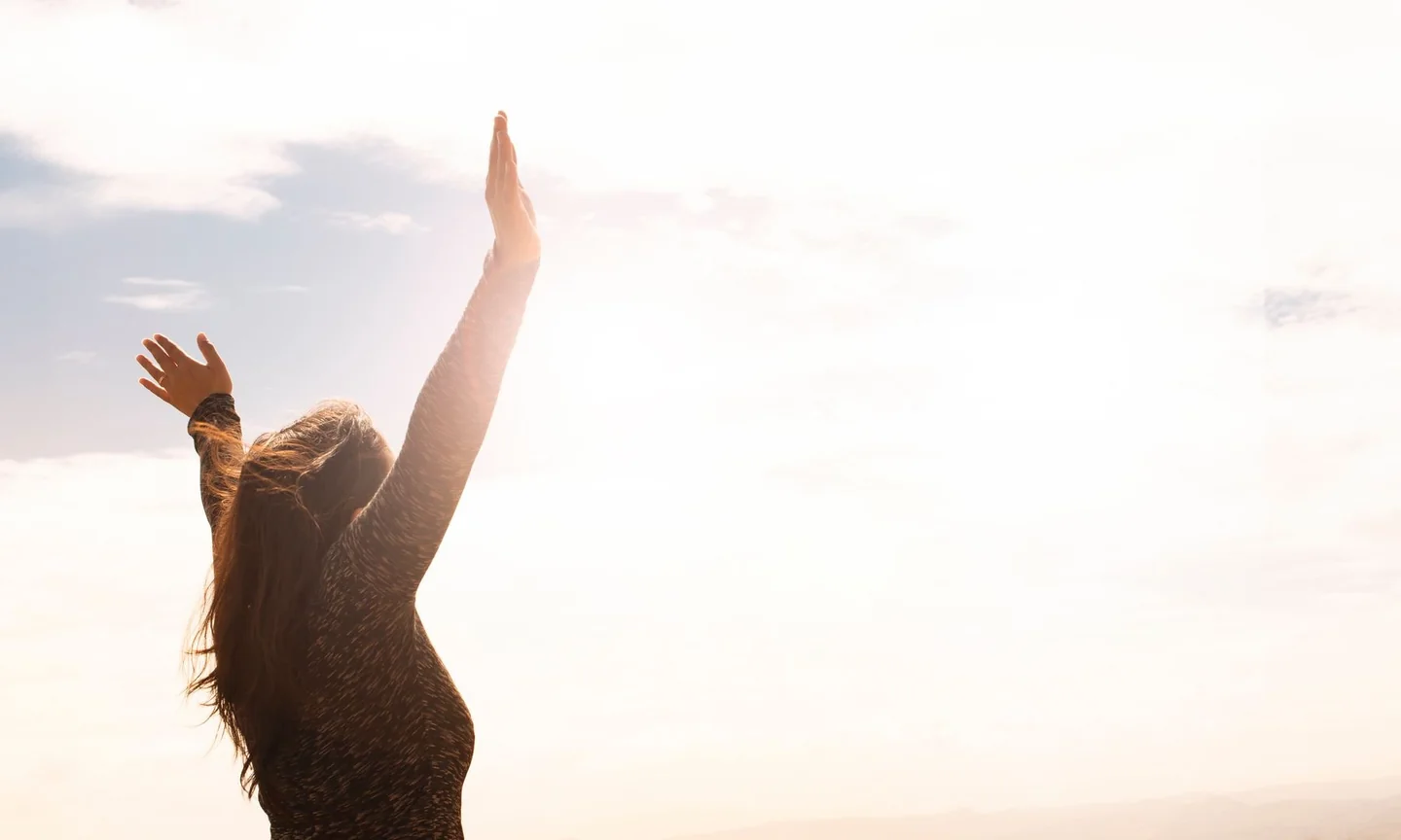 A person lifting their arms in warm daylight outdoors