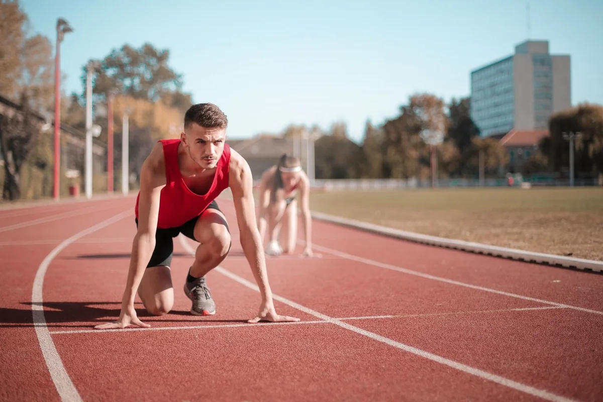 Sprinter preparing on an outdoor track, with a MeDash watermark in the lower right
