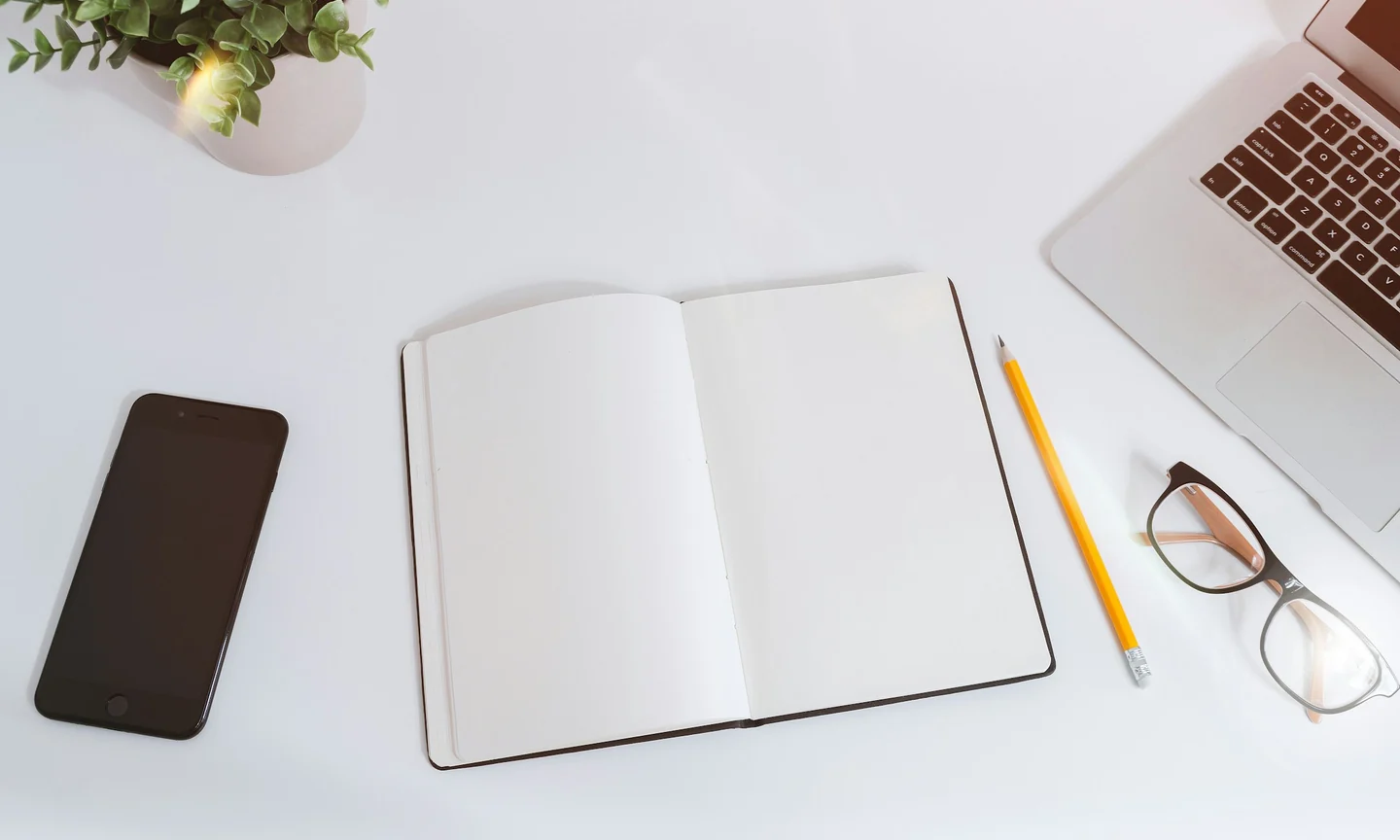 Notebook, phone and laptop on a bright planning desk